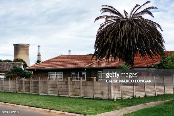 The towers of Eskom Power plant in Hendrina are seen next to a house in the complex where employees live, on February 22, 2018 AFP PHOTO/MARCO...