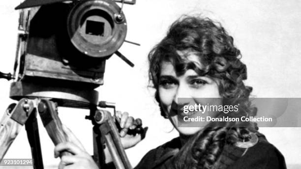 American-Canadian actress Mary Pickford poses for a portrait with a movie camera on a beach, circa 1916.