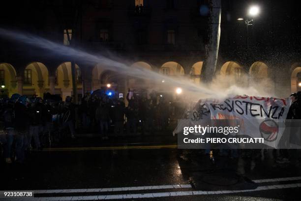 Antifascist activists protect themselves from water cannon used by police officers during a rally against an election campaign meeting organized by...