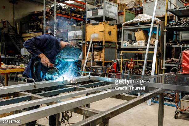 metalen werknemer lassen in fabriek - metal sanding stockfoto's en -beelden