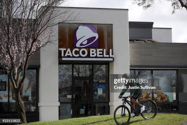 Customer rides his bike in front of a Taco Bell restaurant on February 22, 2018 in Novato, California. Taco Bell has become the fourth-largest...