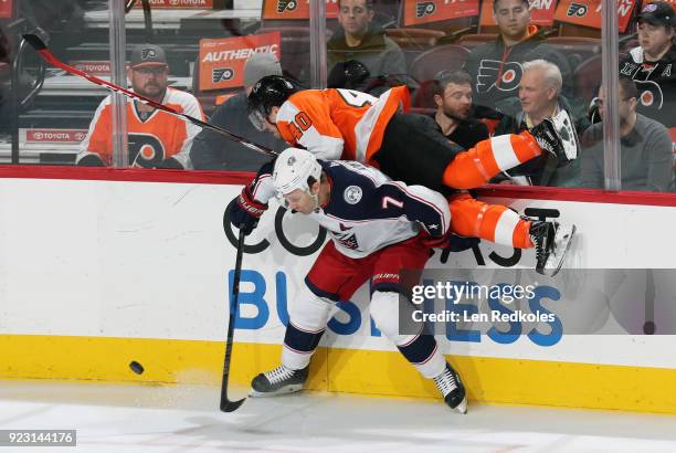 Jordan Weal of the Philadelphia Flyers is checked into mid-air by Jack Johnson of the Columbus Blue Jackets as they battle along the boards for the...