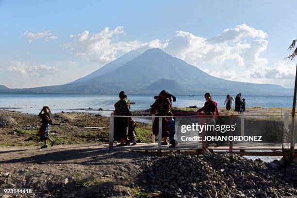 Indigenous people walk along the banks of Lake Atitlan in the highlands in Panajachel municipality, Solola department, 65 km west of Guatemala City,...