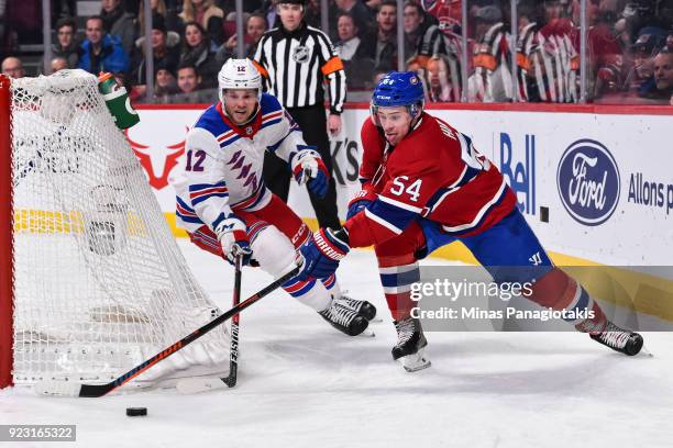 Charles Hudon of the Montreal Canadiens skates the puck against Peter Holland of the New York Rangers during the NHL game at the Bell Centre on...