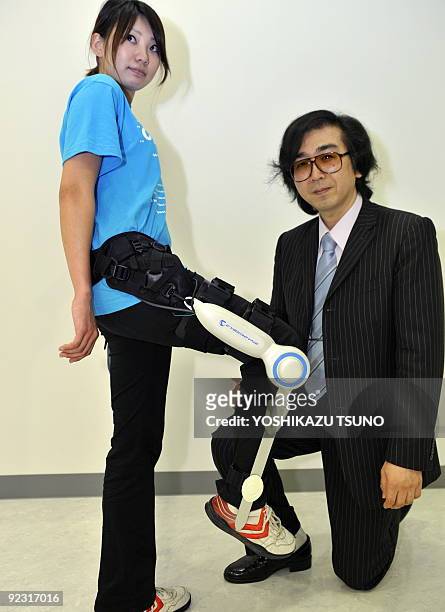Yoshiyuki Sankai, a professor at Japan's Tsukuba University kneels as a girl demonstrates the new robot suit "HAL" , produced by Sankai's company...