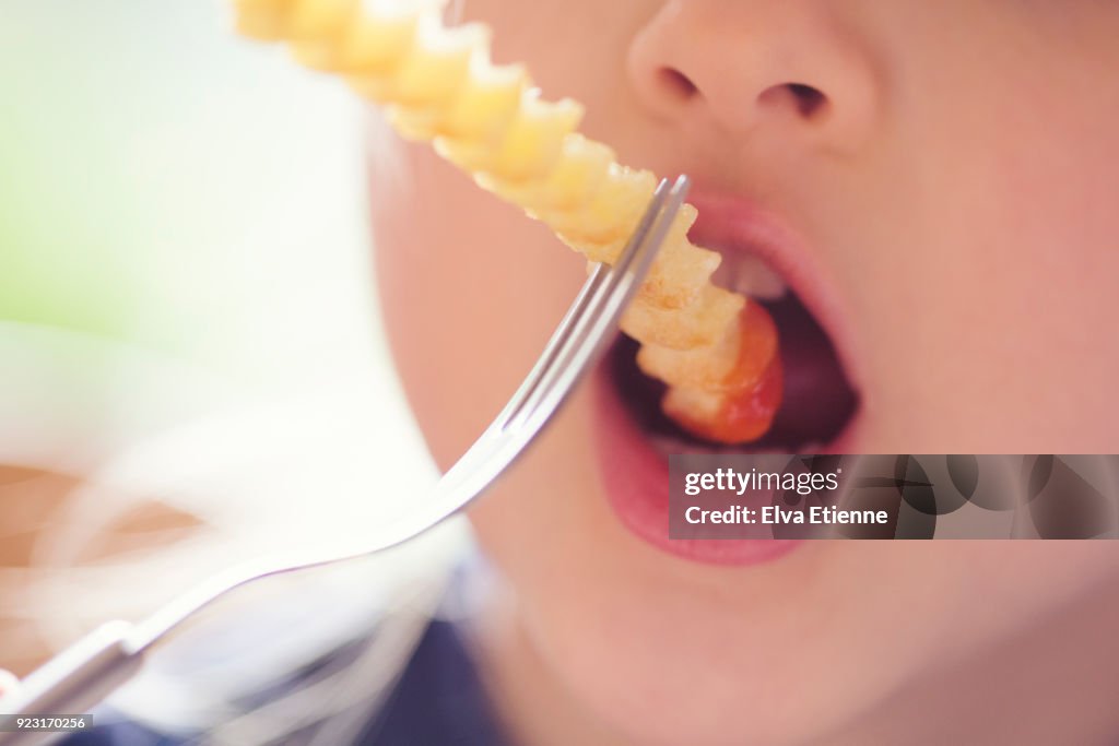 Preschool age child eating crinkle cut fries