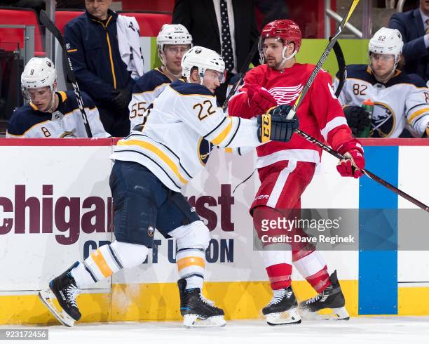 Johan Larsson of the Buffalo Sabres battles for position in front of the bench with Xavier Ouellet of the Detroit Red Wings during an NHL game at...
