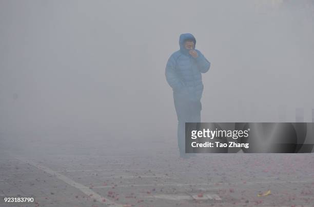 Man walks past the street under heavy pollution as Chinese merchants set off firecrackers to pray for business boomingin front of a wholesale market...