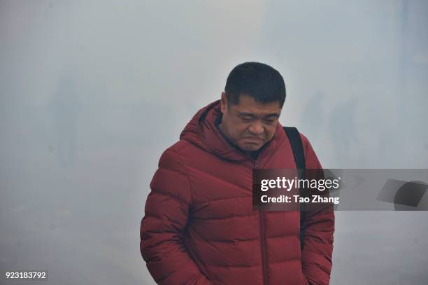 Man walks past the street under heavy pollution as Chinese merchants set off firecrackers to pray for business boomingin front of a wholesale market...