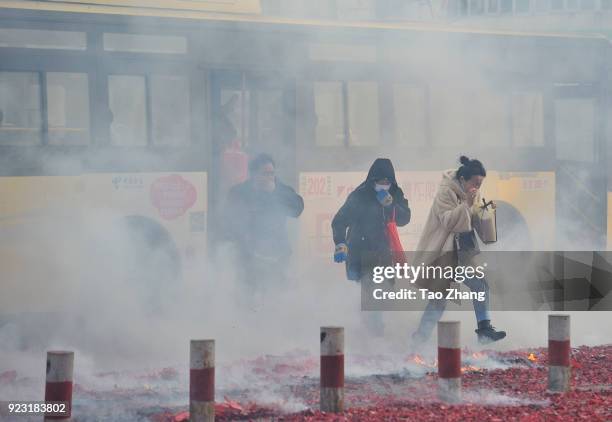 Peopl walk past the street under heavy pollution as Chinese merchants set off firecrackers to pray for business boomingin front of a wholesale market...