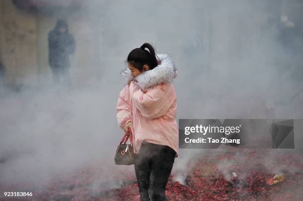 Woman walks past the street under heavy pollution as Chinese merchants set off firecrackers to pray for business boomingin front of a wholesale...