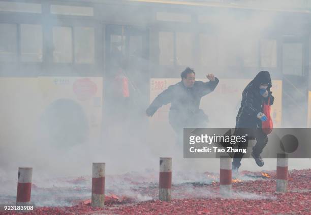 Peopl walk past the street under heavy pollution as Chinese merchants set off firecrackers to pray for business boomingin front of a wholesale market...