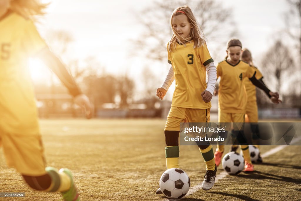 Female Girl Soccer Team running drills at football training
