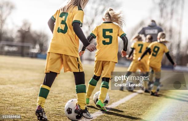 middle aged redhead father coaching soccer to a girl football team at training - sports training drill stock pictures, royalty-free photos & images