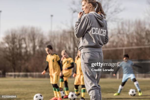 young blonde weibliche fußball-trainer und ihre mädchen-fußball-nationalmannschaft - sports drill stock-fotos und bilder