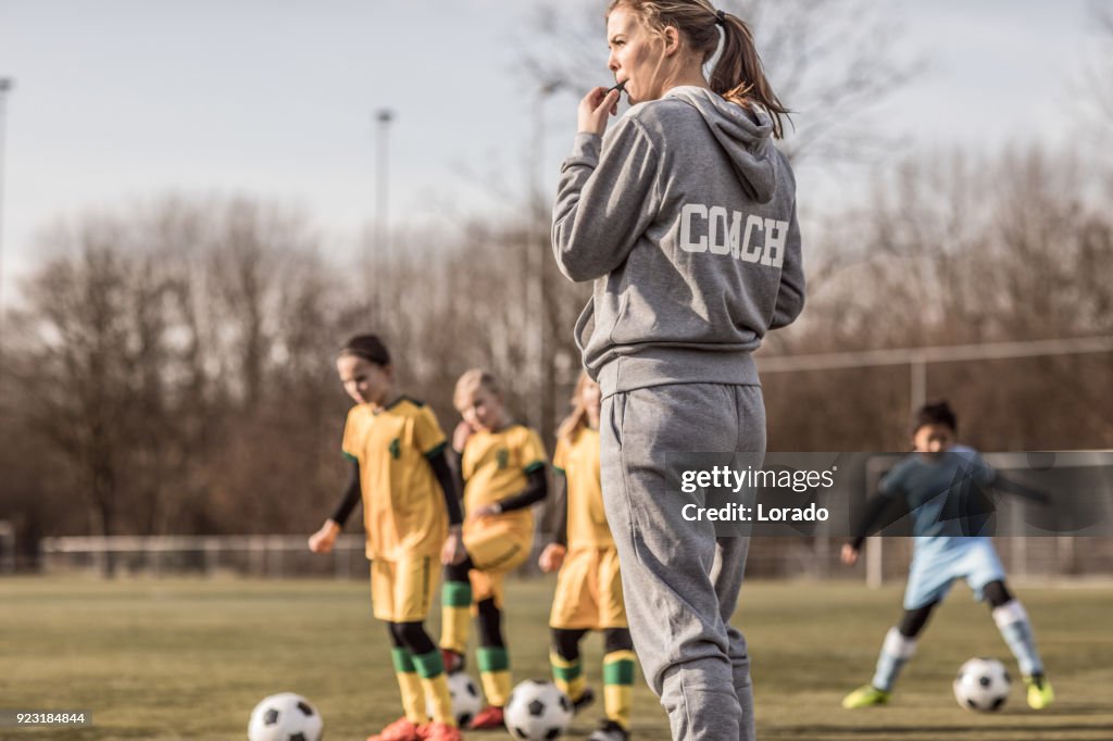 Young Blonde Female Soccer Coach and her Girl Football team