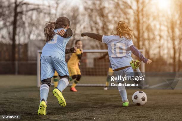 twee vrouwelijke meisje soccer teams spelen van een voetbalwedstrijd van de opleiding in het voorjaar buitenshuis - match sport stockfoto's en -beelden