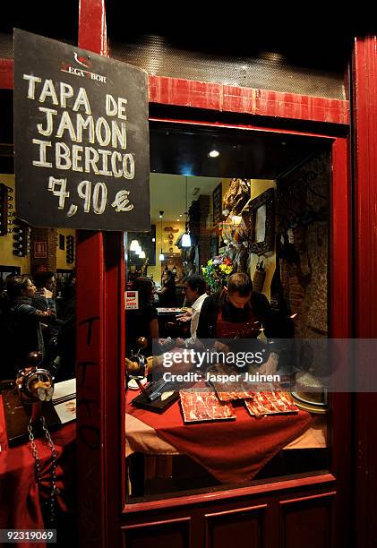 Waiter cuts Jamon Iberico at the entrance of one of the many tapas bars at Calle Cava Baja on October 23, 2009 in Madrid, Spain. While most...