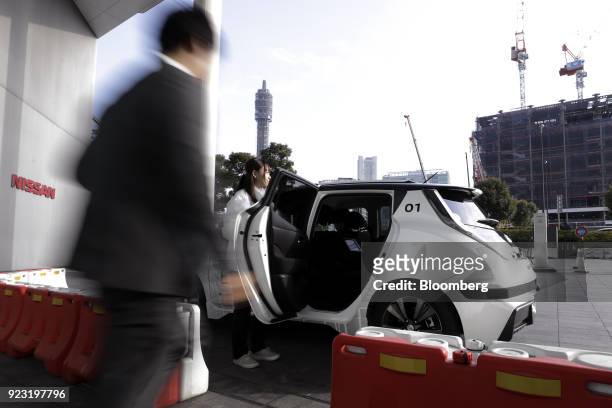 An attendant opens the door of a Nissan Motor Co. Leaf electric vehicle for a Nissan employee ahead of a test drive of the "Easy Ride" robot taxi...