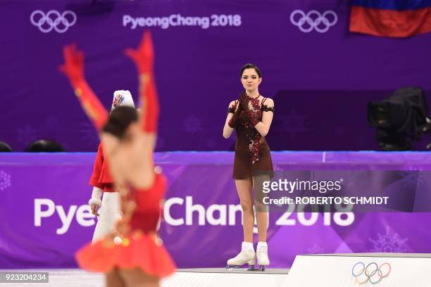 Gold medallist Russia's Alina Zagitova celebrates as silver medallist Russia's Evgenia Medvedeva claps before the venue ceremony after the women's...