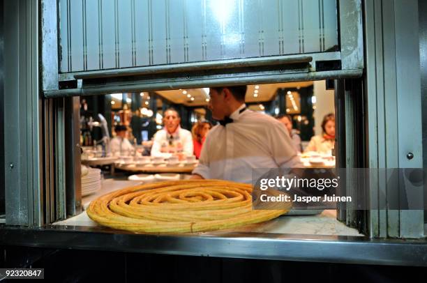 Waiter takes freshly fried Churros through a window from the kitchen at the San Gines Chocolateria on October 23, 2009 in Madrid, Spain. The ridged...