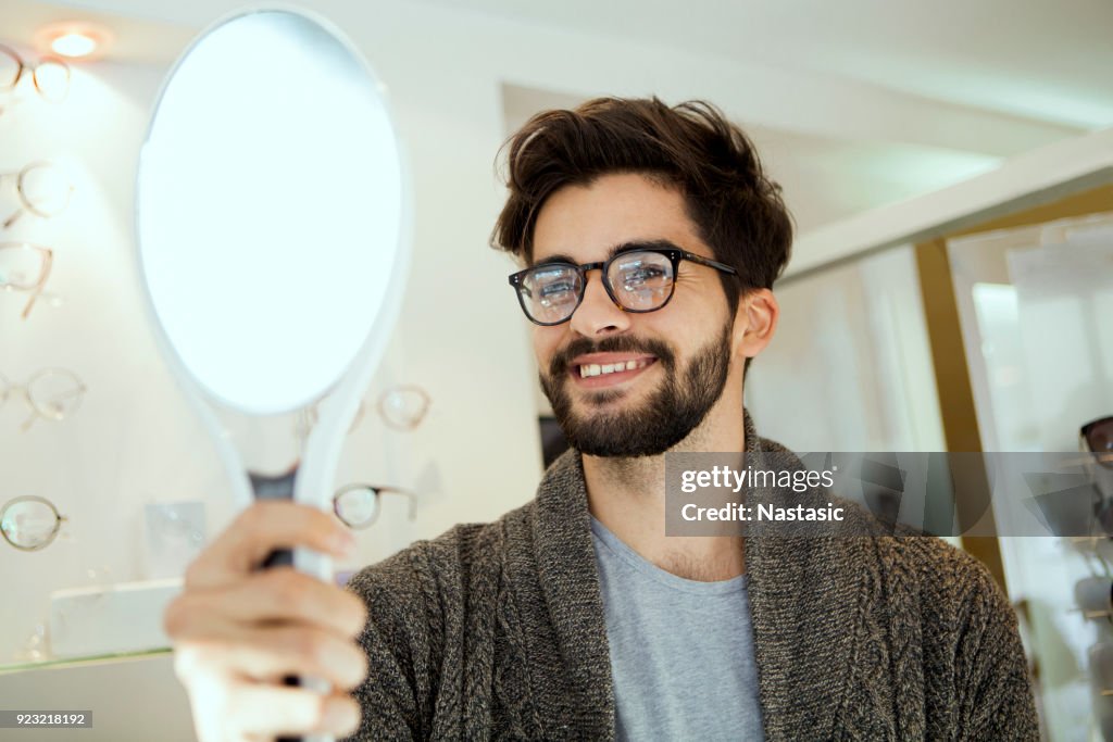Man choosing wearing glasses in optical store
