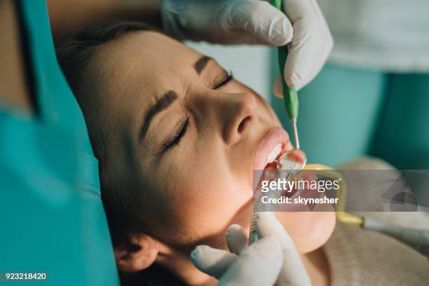 primo primo di donna che soffre durante la procedura di perforazione dentale. - rimotore di placca foto e immagini stock