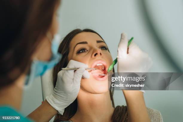 sopra la vista della giovane donna che si ha i denti esaminati nell'ufficio del dentista. - rimotore di placca foto e immagini stock