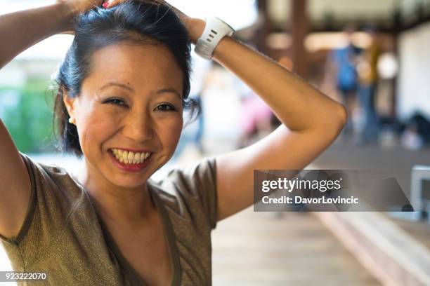 voorkant kijk een portret van een lachende vrouw, die verantwoordelijk is voor haar haren in zen tuin van chion-ji tempel in kyoto, japan - kumikomini stockfoto's en -beelden