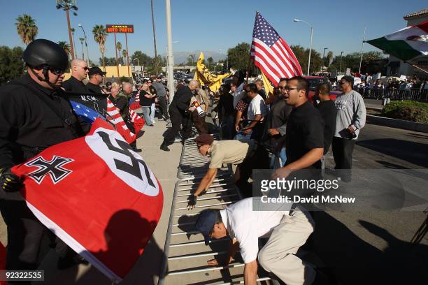 Counter-protesters knock down a barrier between them and the white supremacist group, the National Socialist Movement, during the NSM's anti-illegal...