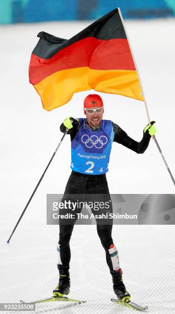 Johannes Rydzek of Germany wave the national flag as he celebrates winning the gold medal in the Nordic Combined Team Gundersen Large Hill/4x5km...