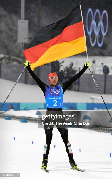 Johannes Rydzek of Germany wave the national flag as he celebrates winning the gold medal in the Nordic Combined Team Gundersen Large Hill/4x5km...