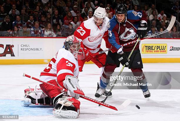 Goaltender Jimmy Howard of the Detroit Red Wings makes a save against Chris Stewart of the Colorado Avalanche as Red Wings' Brad Stuart looks on at...