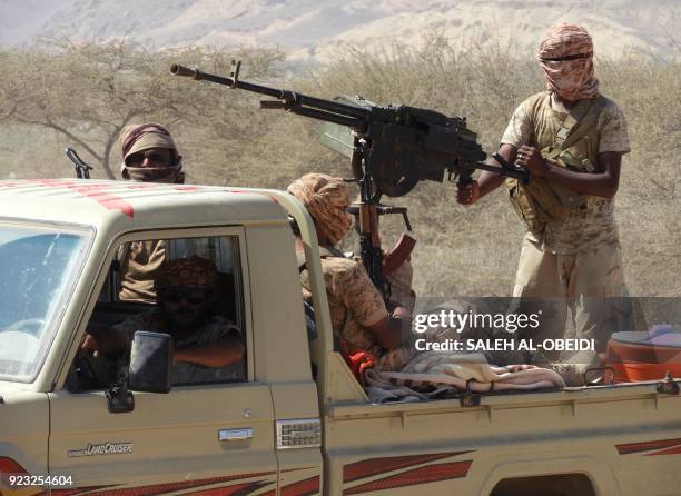 Yemeni fighters loyal to the government backed by the Saudi-led coalition fighting in the country ride in the back of a pickup truck with mounted...