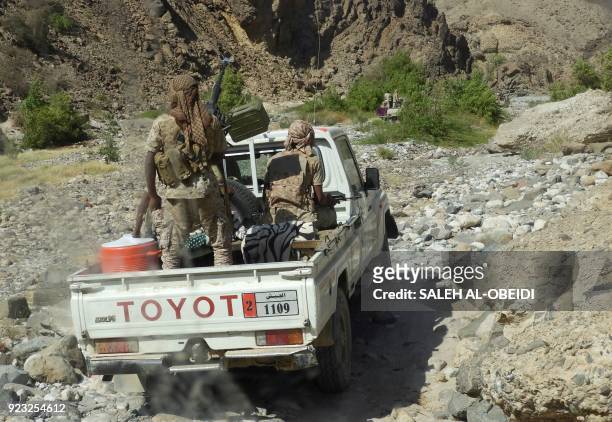 Yemeni fighters loyal to the government backed by the Saudi-led coalition fighting in the country ride in the back of a pickup truck with mounted...