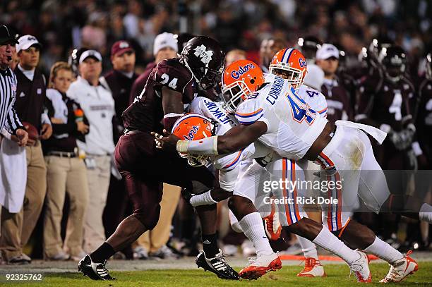 Running back Anthony Dixon of the Mississippi State Bulldogs is tackled by Jermaine Cunningham and Janoris Jenkins of the Florida Gators, at Davis...