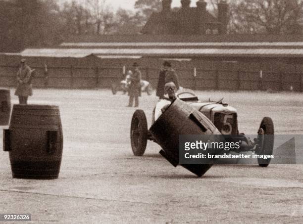 Motor Racing at Brooklands motor racing circuit: R.C. Fairfield in his Riley coliding with a barrel. Weybride, Surrey. England. Photograph. 1934.