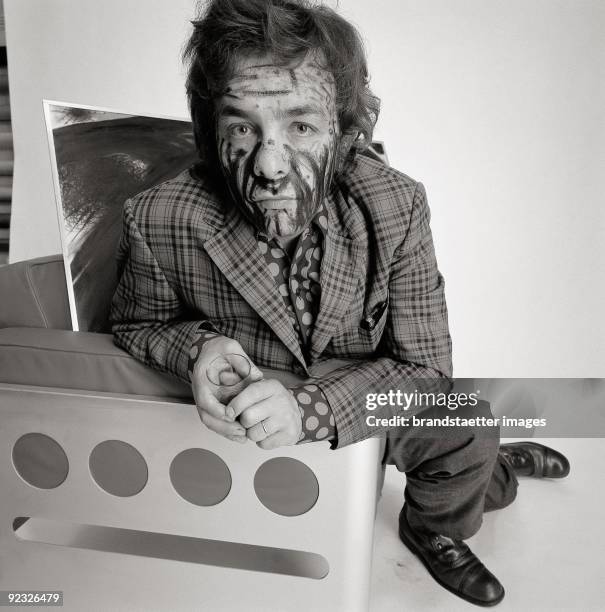 Austrian painter Arnulf Rainer in the studio of Christian Skrein. He sits in a chair designed by Walter Pichler . Austria. Photograph. 1968.