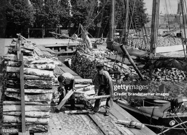 Loading of birchwood for the prouction of vesta . Sailing boats convey birchwood from the fjords to Stockholm. Photograph. Stockholm. Schweden. 1935.