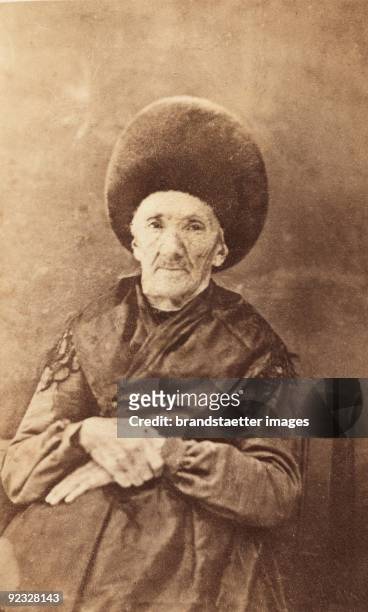 Old countrywoman wearing the traditional costume of Lech am Arlberg, Vorarlberg. Notice the hat made from otter fur. Austria. Photograph. Around 1890.
