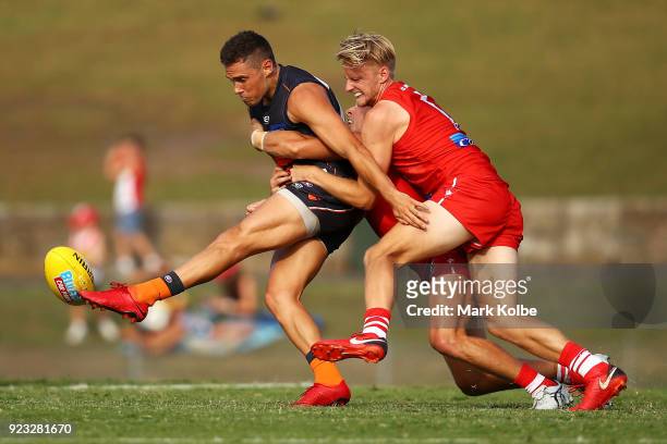 Josh Kelly of the Giants kicks as he is tackled by Kieren Jack and James Rose of the Swans during the AFL Inter Club match between the Sydney Swans...