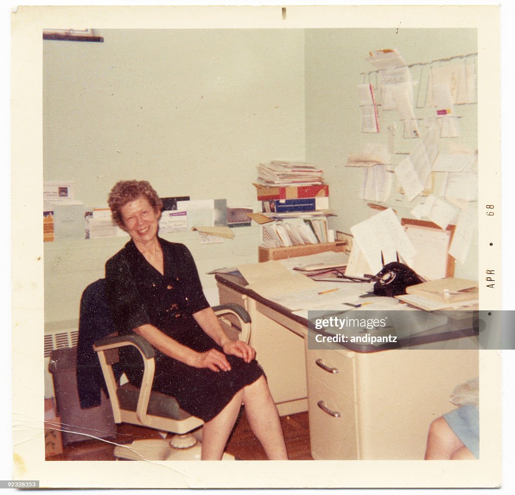 Vintage photograph of an happy secretary sitting at her desk