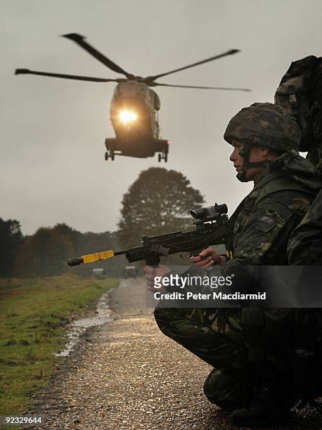 Members of 1 Force Protection Wing of the Royal Air Force Regiment wait as a helicopter takes off with a simulated casualty on board during a mission...