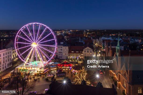 Illuminated Ferris wheel at evening Christmas market in winter at Koberg, Hanseatic town Luebeck, Germany.