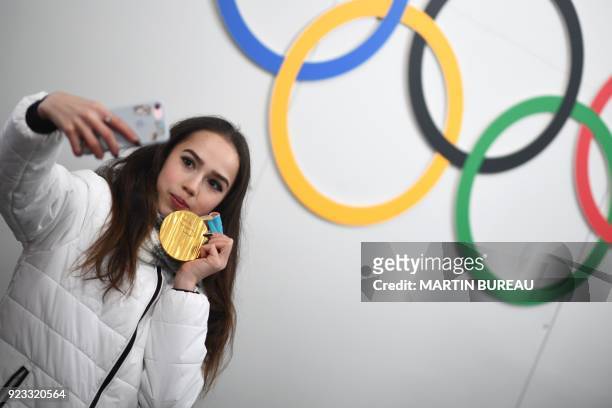 Russia's figure skating gold medallist Alina Zagitova poses for a selfie in front of Olympic rings backstage at the Athletes' Lounge during the medal...