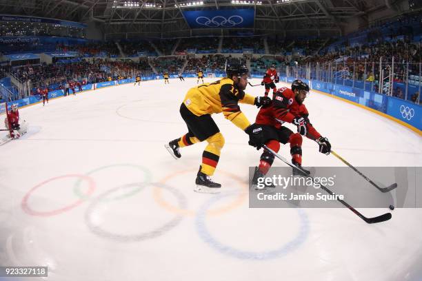 Andrew Ebbett of Canada fights for control of the puck with Marcus Kink of Germany in the first period during the Men's Play-offs Semifinals on day...