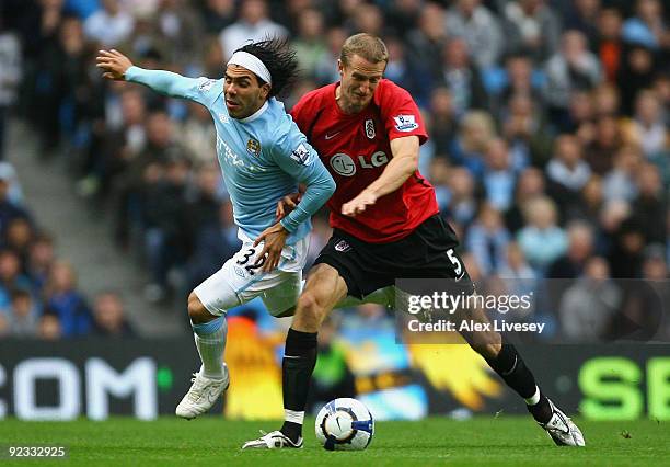 Brede Hangeland of Fulham tackles Carlos Tevez of Manchester City during the Barclays Premier League match between Manchester City and Fulham at the...