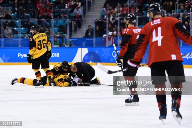 Teammates check on Germany's David Wolf as he lies on the ice after being hit in the men's semi-final ice hockey match between Canada and Germany...