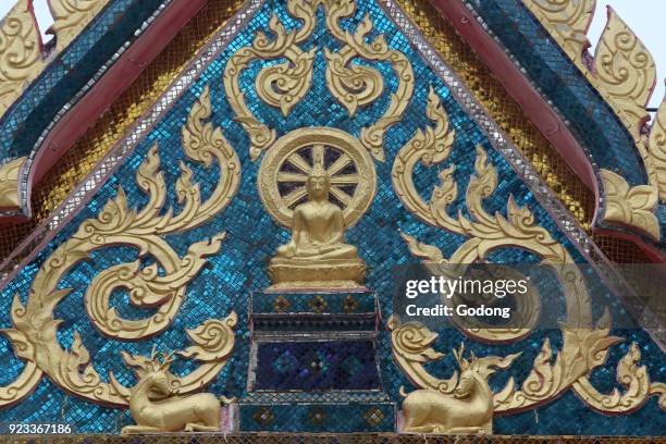 Buddha and wheel of dharma on a tympanum in a Hua Hin temple. Thailand.