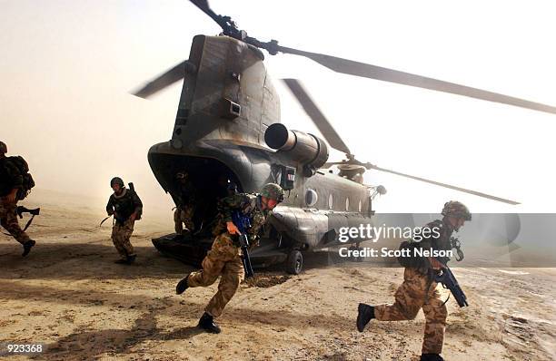 British Royal Marines of 45 Commando scramble out the back of a Chinook helicopter during an eagle vehicle check point operation as part of the...